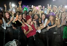 小賈斯汀魅力橫掃Coachella 預告:很快再見 Male singer in a red beanie performs at a crowded concert, fans reach over the barrier with phones raised around him.