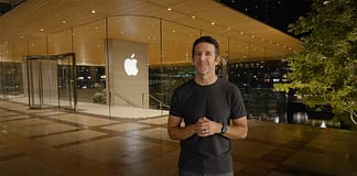 蘋果面臨AI浪潮的定位與發展關鍵節點,選擇 Ternus絕非保守牌:解析新任執行長的AI扶植戰力 Man in a black t-shirt and jeans stands outside an Apple Store at night, hands clasped in front.